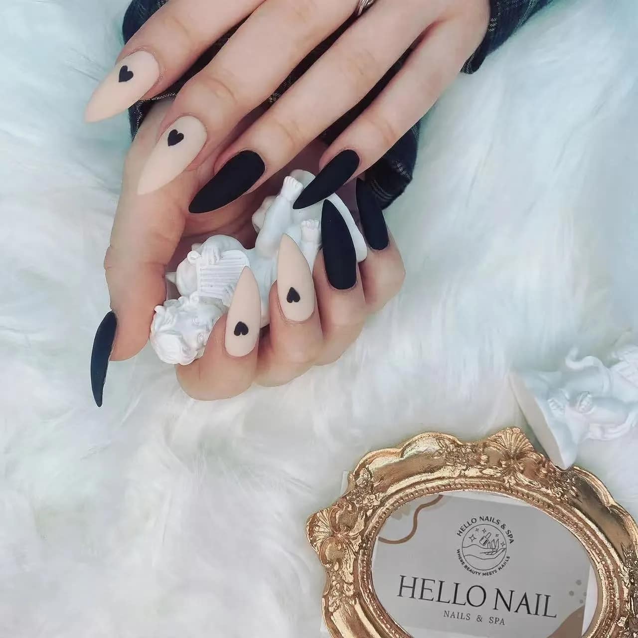 Matte black and nude stiletto nails with heart accents